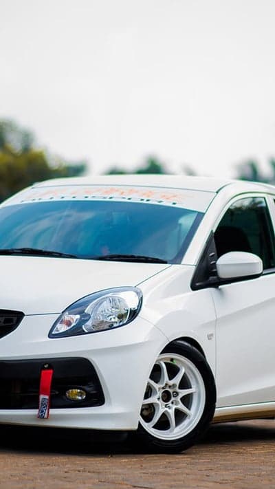 White Honda Brio with Orange Sun Visor and Tow Hook