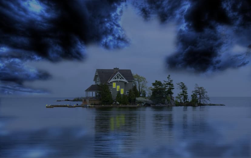 Small cottage with glowing windows on a rocky island under a dark, stormy sky surrounded by churning ocean waves.