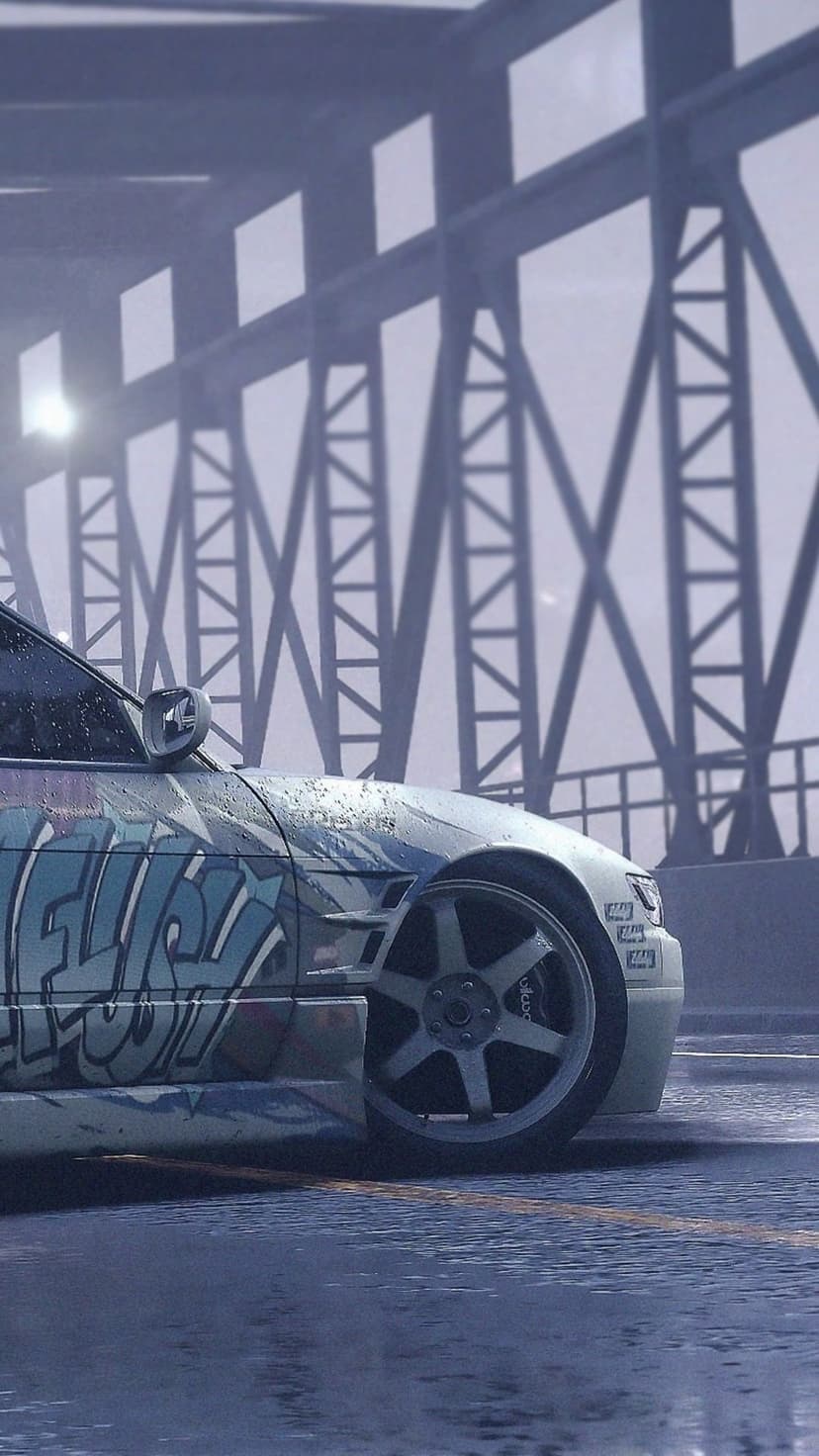 Graffiti-covered car parked on a wet street under a metal bridge structure during a foggy, rainy afternoon.
