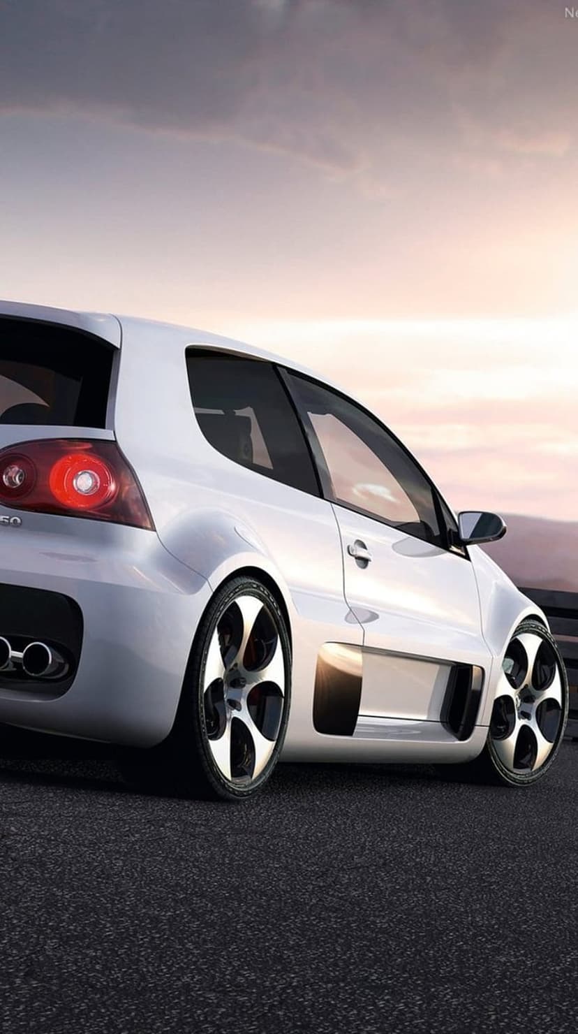 White Volkswagen Golf R32 rear profile parked on a mountain road during a hazy sunset with dual exhaust pipes.