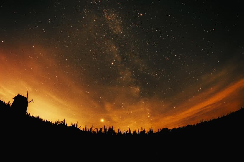 Silhouetted windmill on a hill beneath a vast Milky Way galaxy and a warm orange twilight horizon gradient.