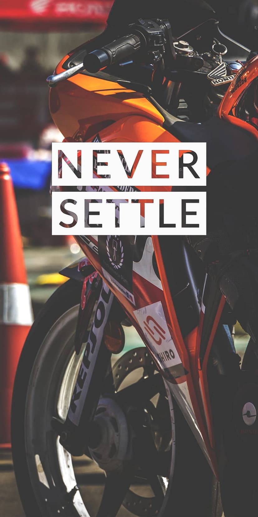 Orange racing sportbike with Never Settle typography displayed on a detailed mechanical close-up background.