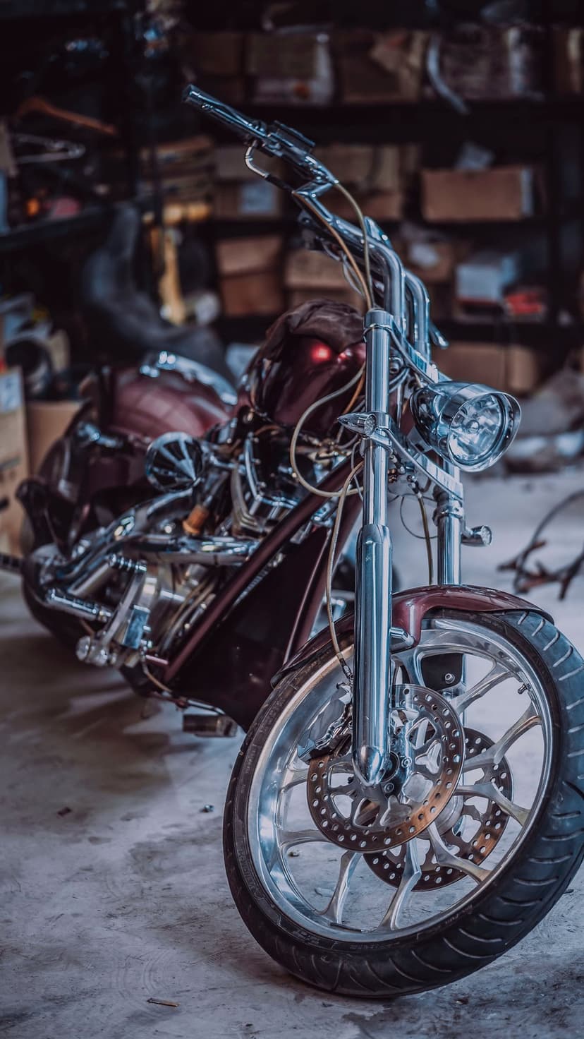 Red custom chopper motorcycle with glowing headlights and chrome engine parts on a concrete garage floor.