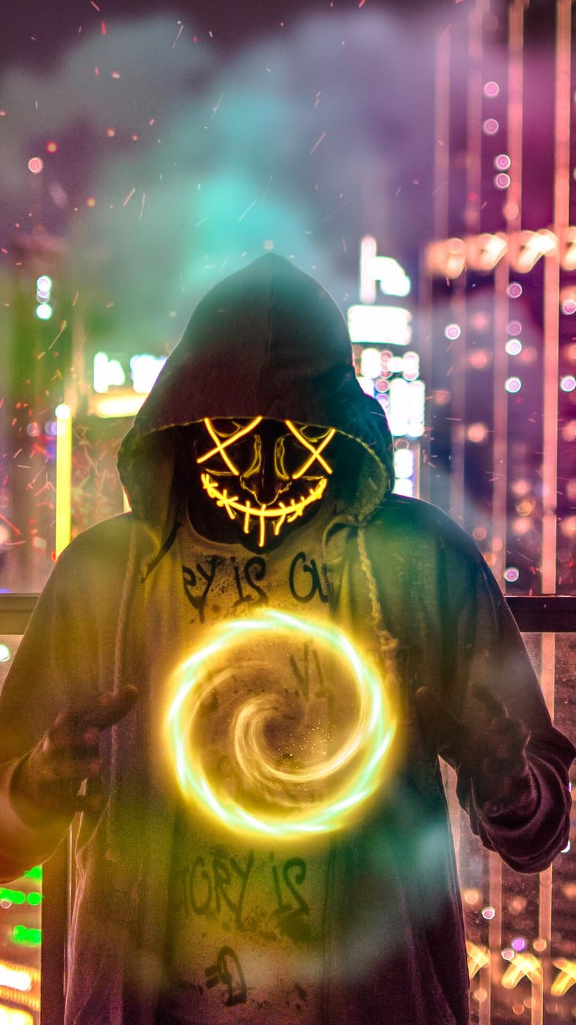 Masked figure in a black hoodie holds a glowing orange orb of light against a blurred night city backdrop.