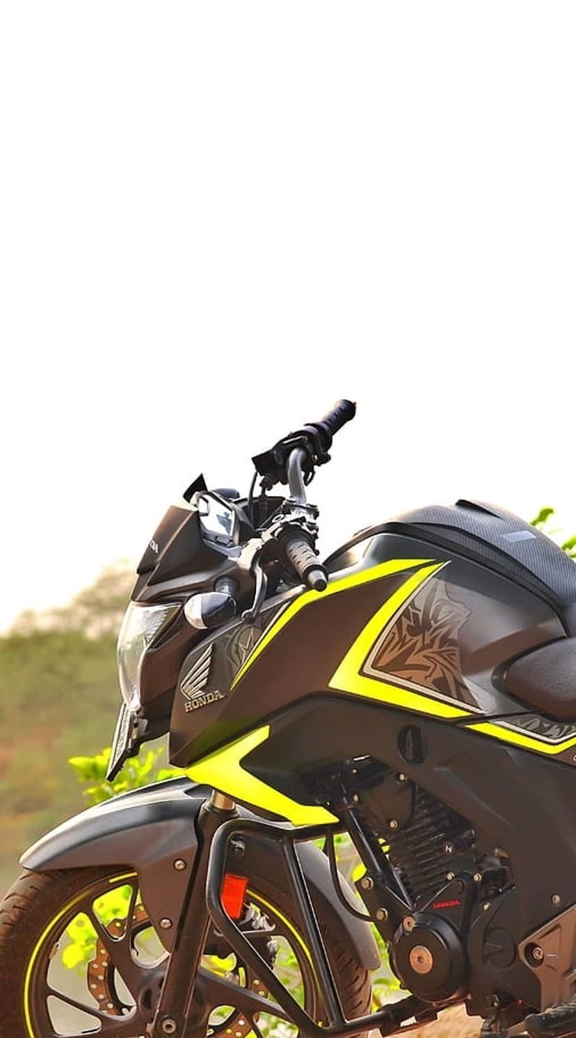 Honda Hornet motorcycle featuring yellow accents and a matte grey body parked against a blurred nature backdrop.