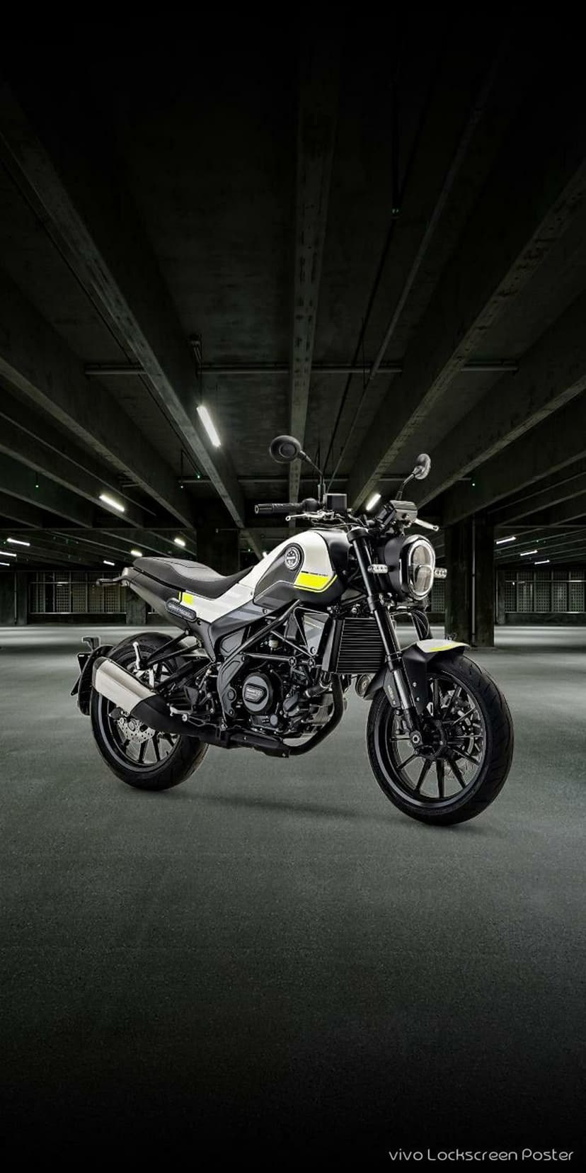 Sporty white and black motorcycle with yellow accents parked in a dimly lit concrete industrial garage setting.