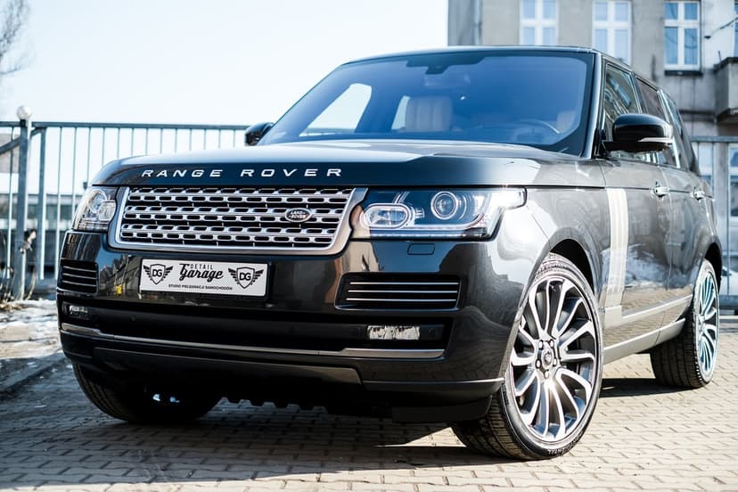 Black Range Rover Vogue with custom multi-spoke wheels shown from a low front angle against a neutral background.