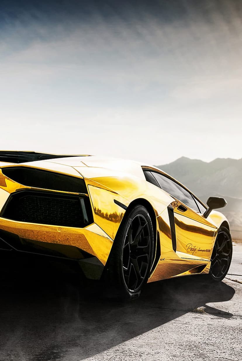Gold Lamborghini Aventador speeds on a winding mountain road with dust trailing from black performance wheels.
