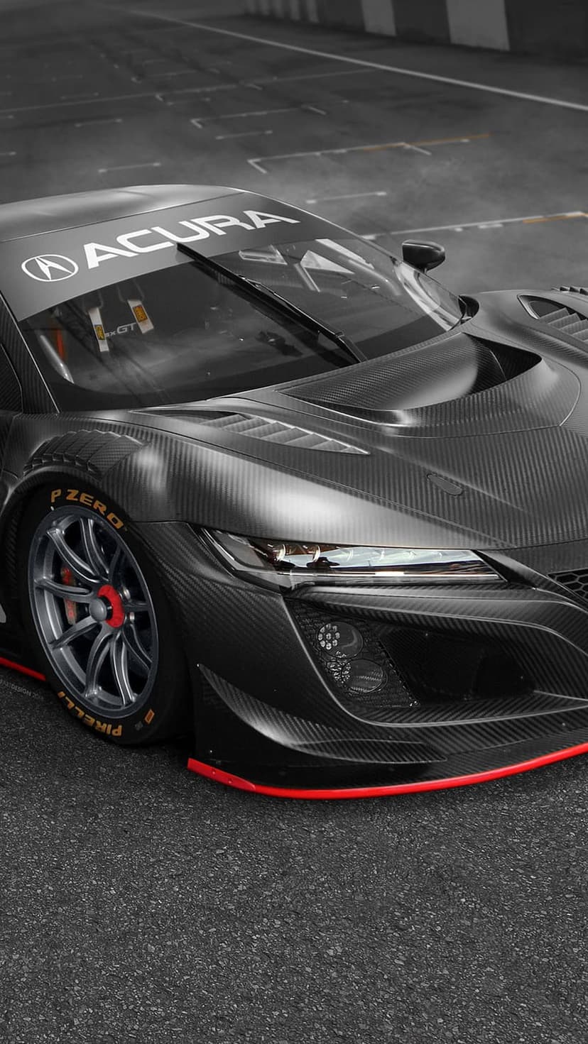 Acura NSX GT race car with a visible carbon fiber body and red accents parked on a textured asphalt race track.