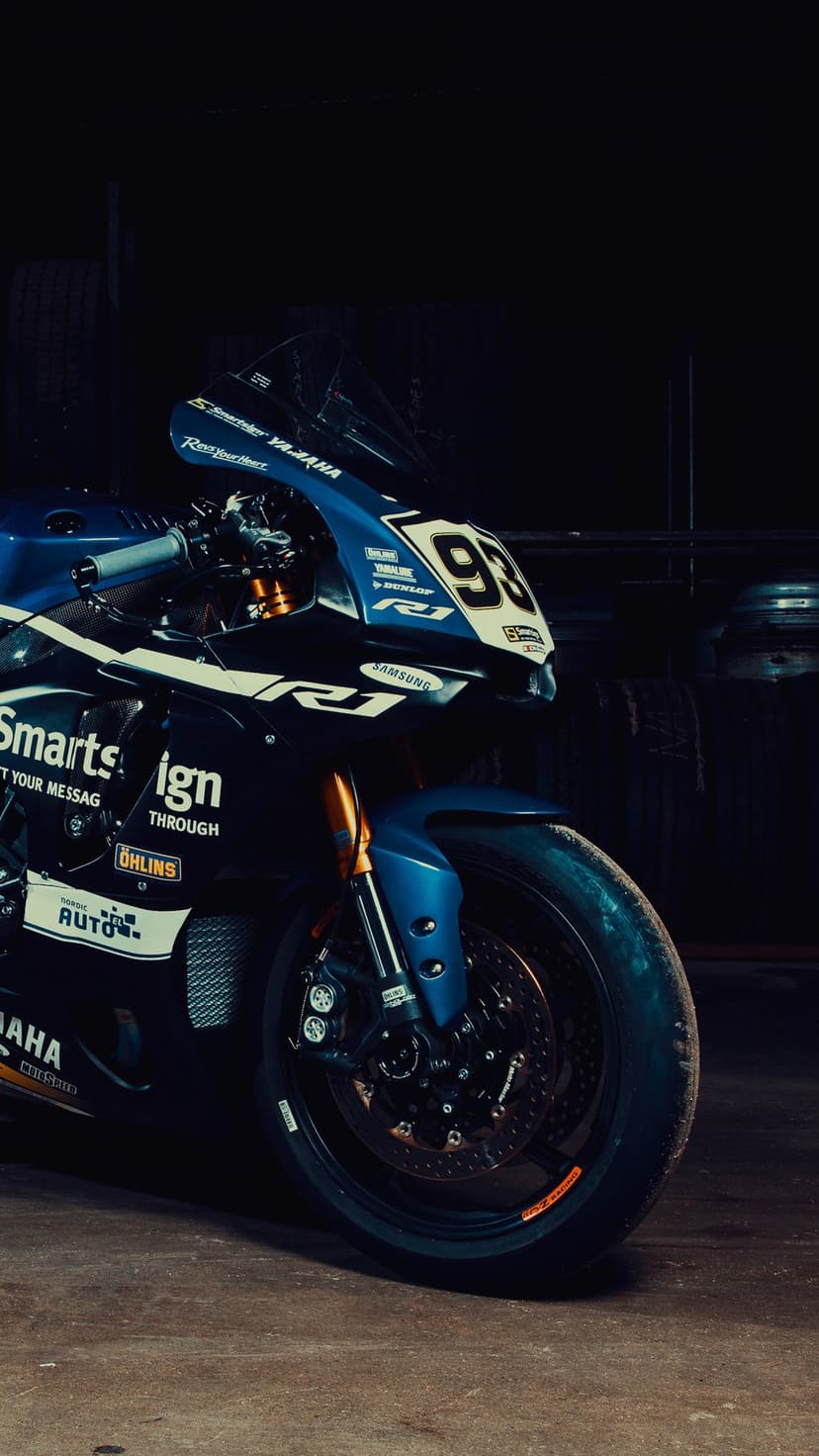 Yamaha R1 racing motorcycle with blue livery and number 93 in a dark garage under cinematic light.