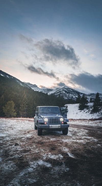 Jeep Wrangler on snowy mountain road at dusk