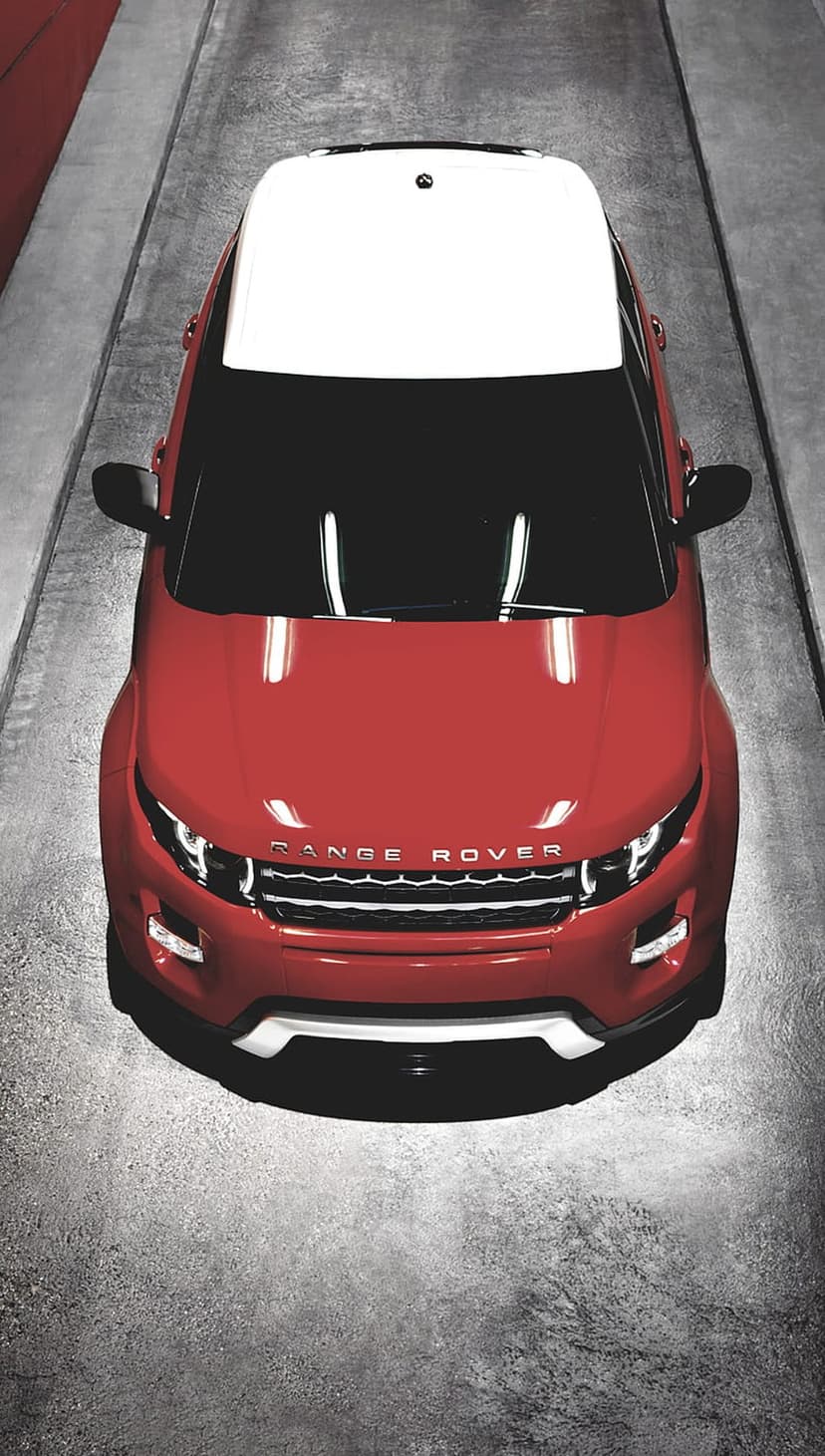 Red Range Rover Evoque with a white roof on textured concrete viewed from a top-down bird's-eye perspective.
