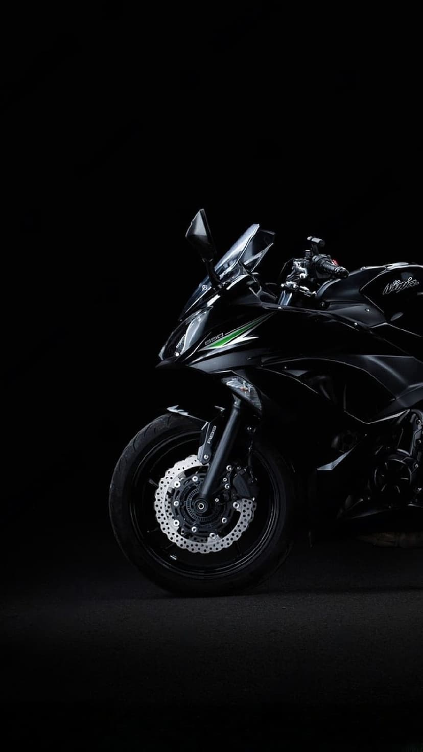 Kawasaki Ninja front wheel and disc brakes with green accents against a solid black studio background.