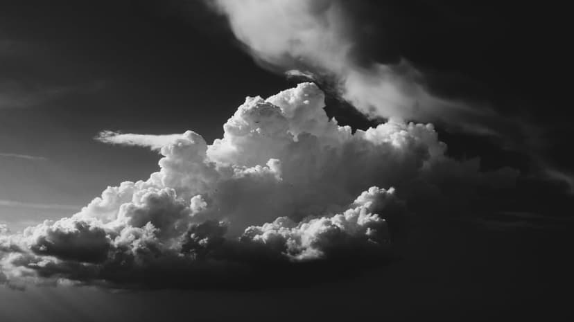Cumulonimbus storm clouds with sunlit peaks and dark shadows create a high-contrast monochrome sky backdrop.