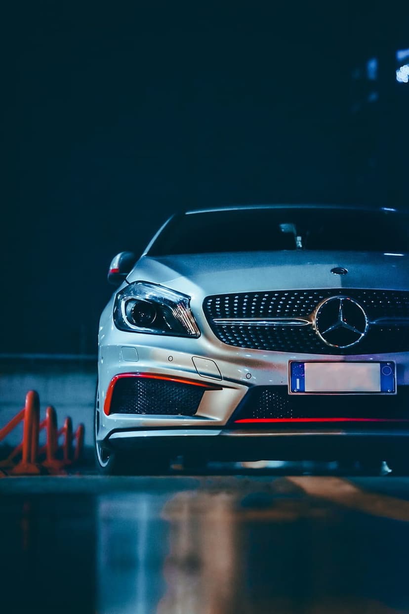 Mercedes-Benz AMG silver grille with a chrome star emblem and LED headlights featuring subtle red interior accents.