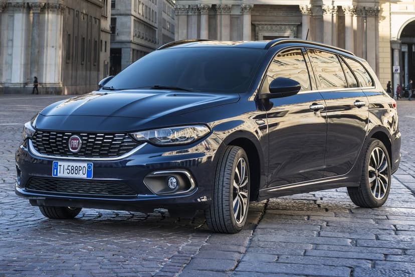 Dark blue Fiat Tipo station wagon parked on a cobblestone plaza with classical architecture in the background.
