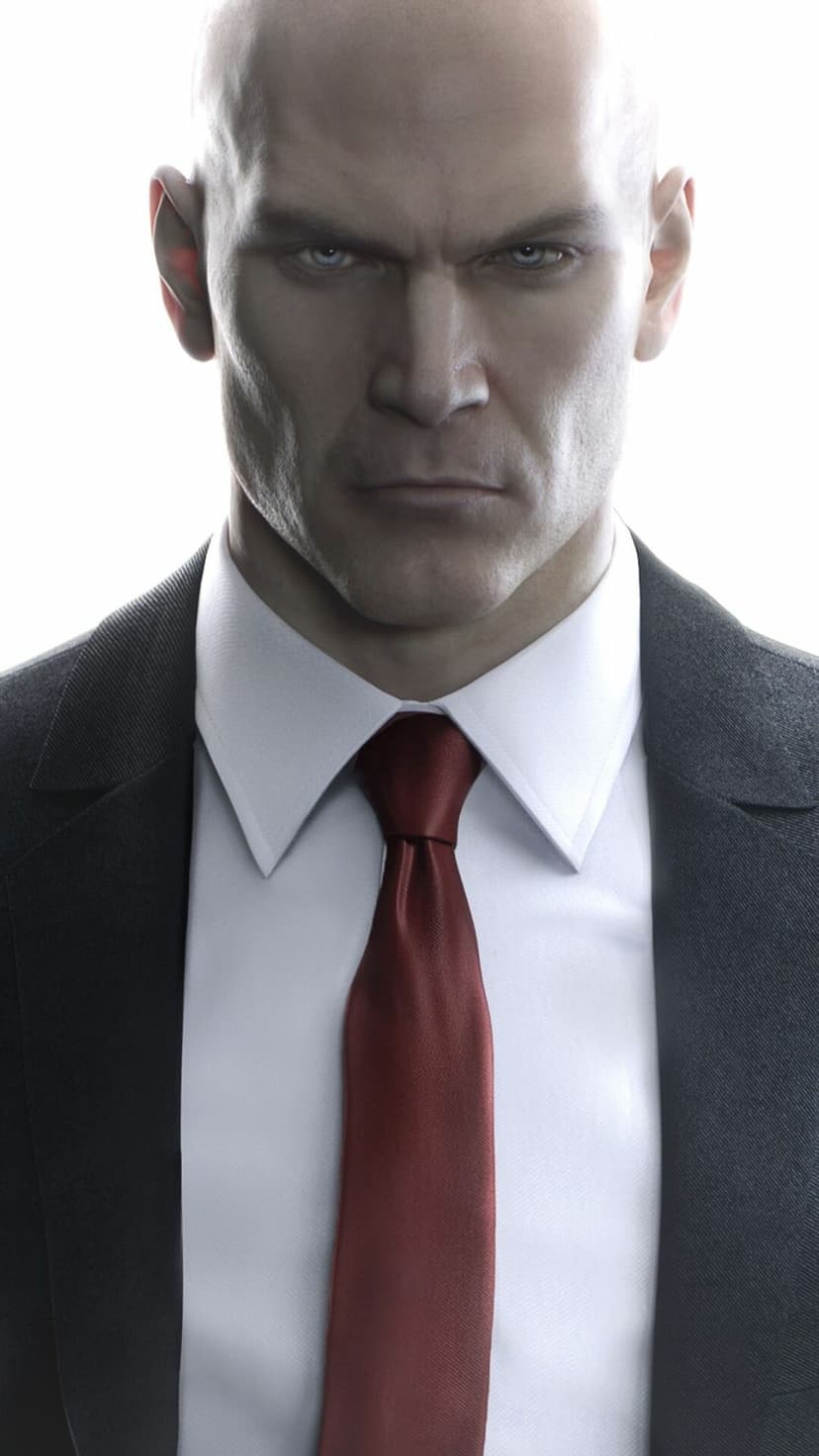 Bald man with blue eyes in a black suit and red tie looking forward against a bright white background.