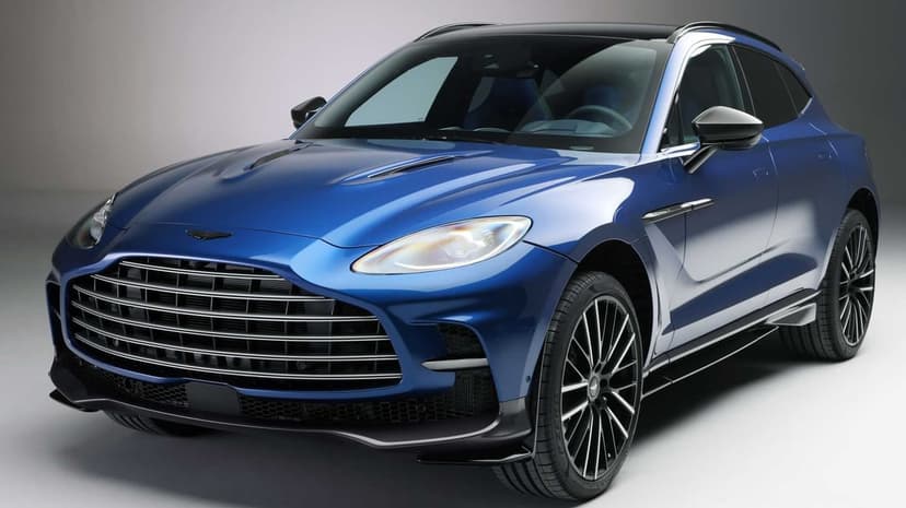 Blue Aston Martin DBX 707 SUV with a large chrome grille and black wheels in a bright, clean studio setting.