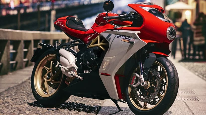Red and gold MV Agusta Superveloce motorcycle parked on a cobblestone street with city lights in the background.