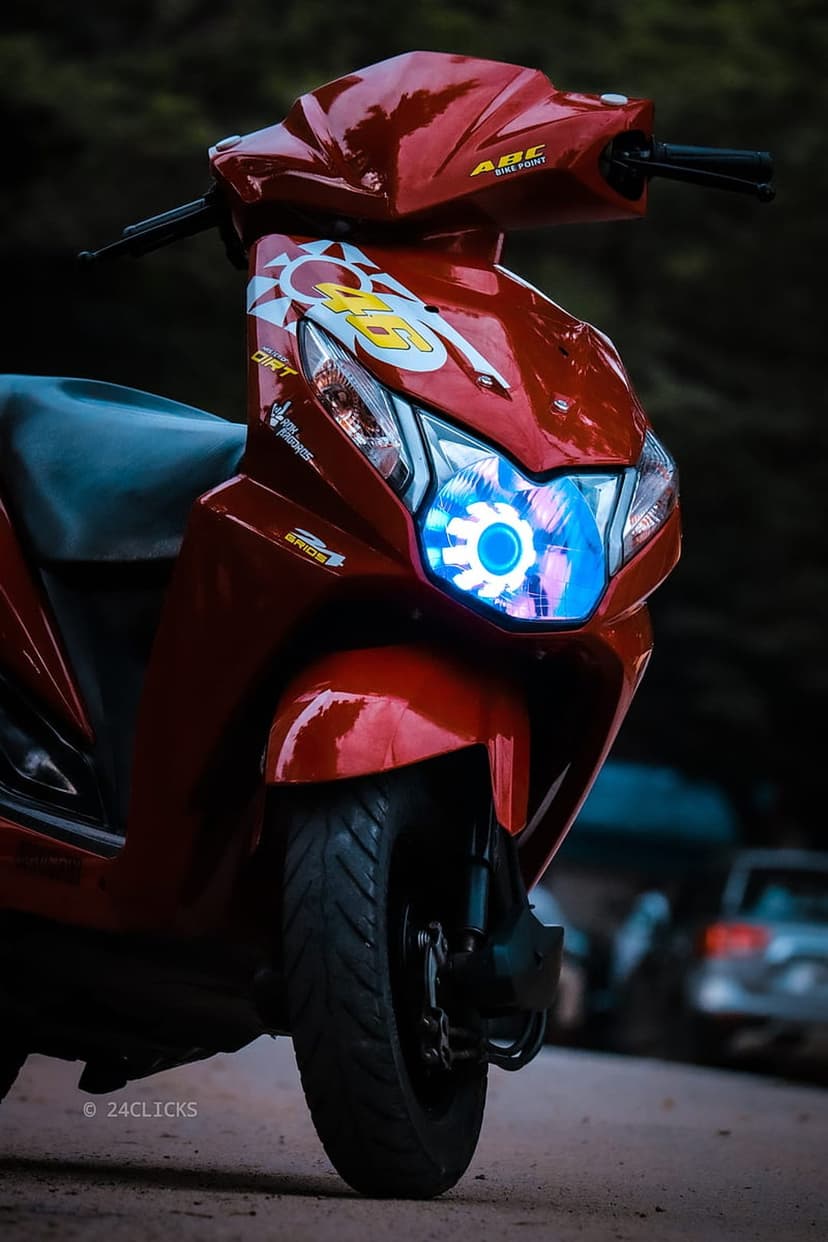 Red scooter featuring a blue halo headlight, number 46 racing graphics, and a sunburst design on its front fairing.