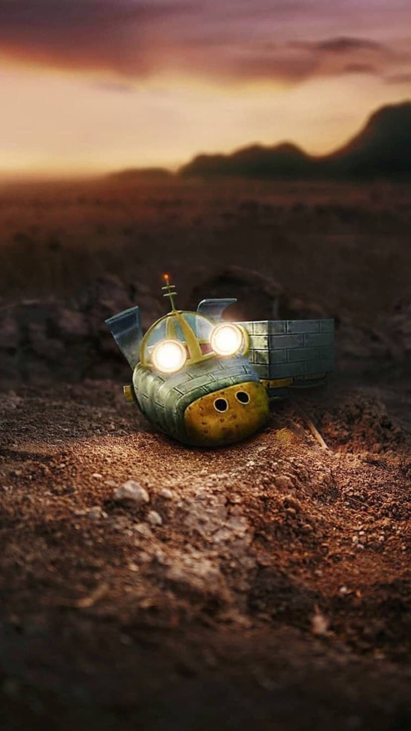 Tiny robot with glowing blue eyes rests on parched earth under a vibrant orange and purple sunset sky.