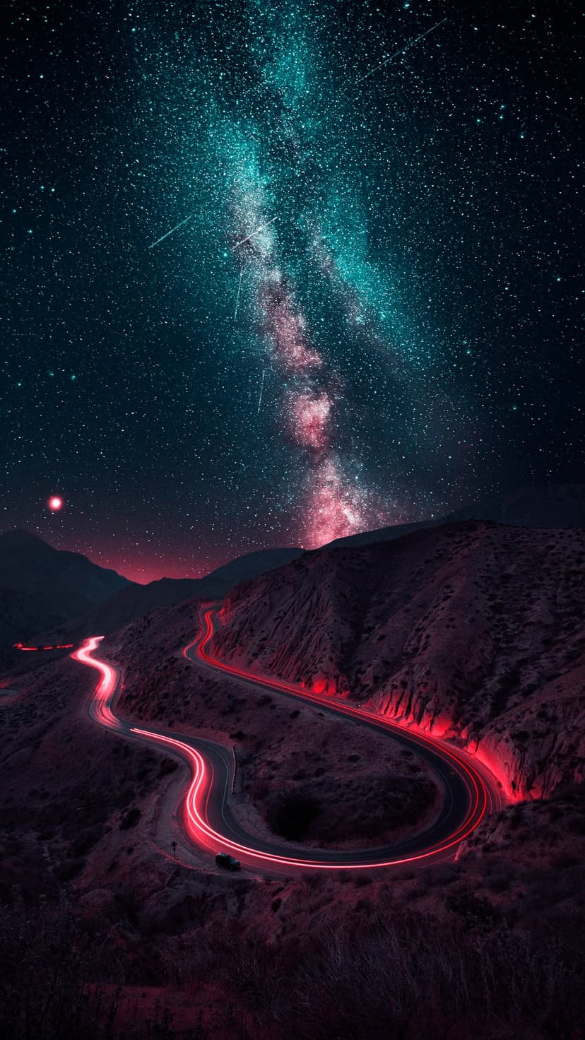 Red light trails wind through desert mountains under a bright Milky Way galaxy and star-filled night sky.