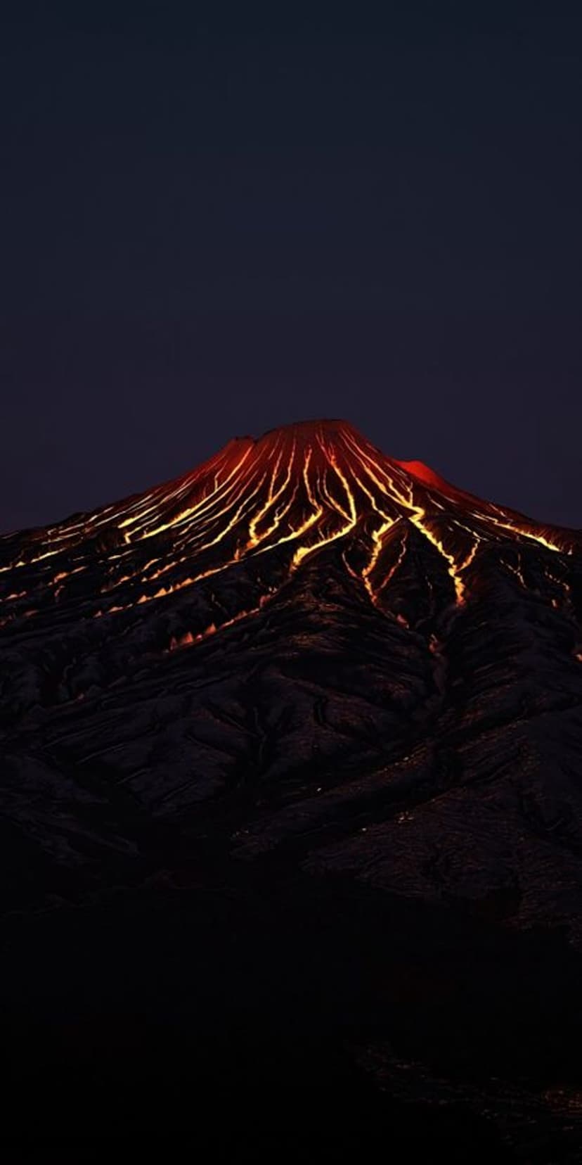Molten orange lava streams down the jagged dark slopes of an active volcano under a starless midnight sky.