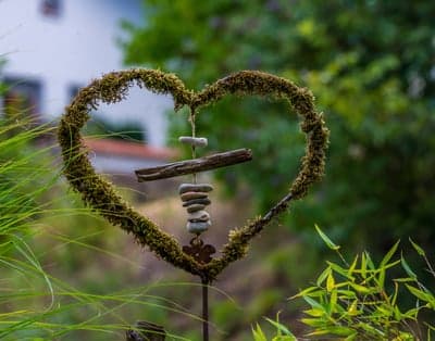 Moss-covered heart sculpture with stacked stones outdoors