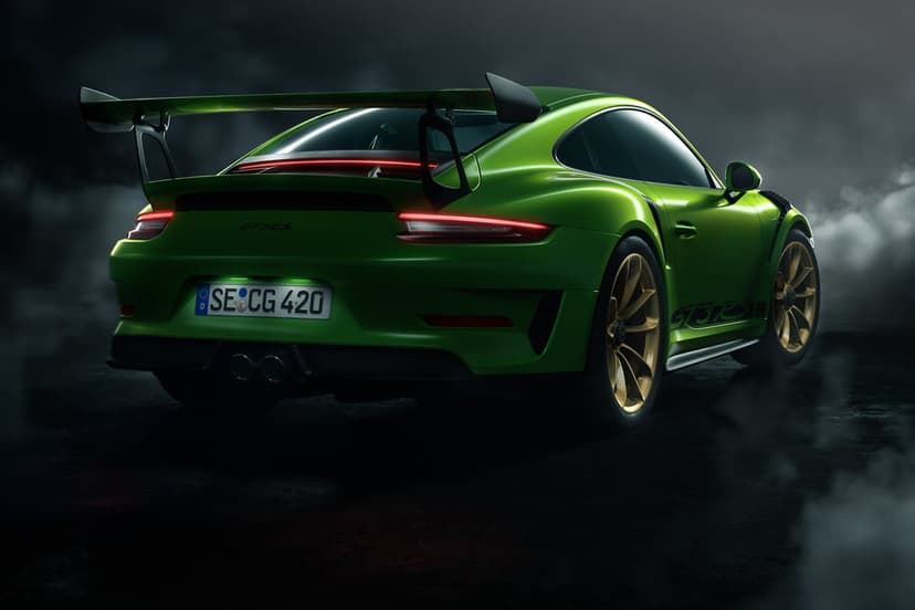 Green Porsche 911 GT3 RS sports car with a large rear wing and glowing taillights in a smoky dark environment.