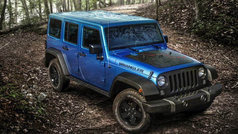 Blue Jeep Wrangler with a topographical hood decal parked on a dirt path in a lush green forest.