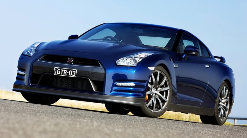Deep blue Nissan GT-R sports car parked on an asphalt road under a clear sky with metallic wheel details.