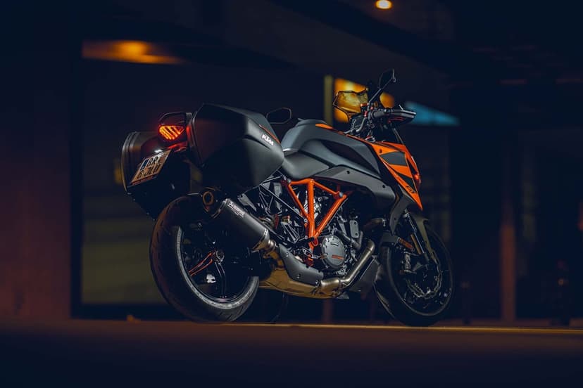 Rear view of a matte black KTM Super Duke GT motorcycle with an orange frame and panniers in a dark city at night.