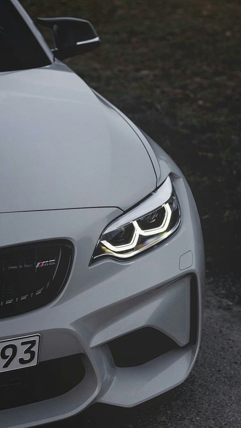 White BMW M2 front headlight and kidney grille with M2 badge shown in a detailed low-angle automotive close-up.