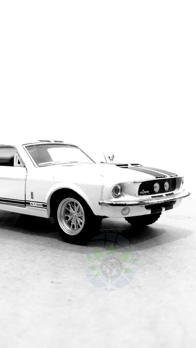 Shelby GT500 model car in black and white displays racing stripes and headlights in a front quarter view.