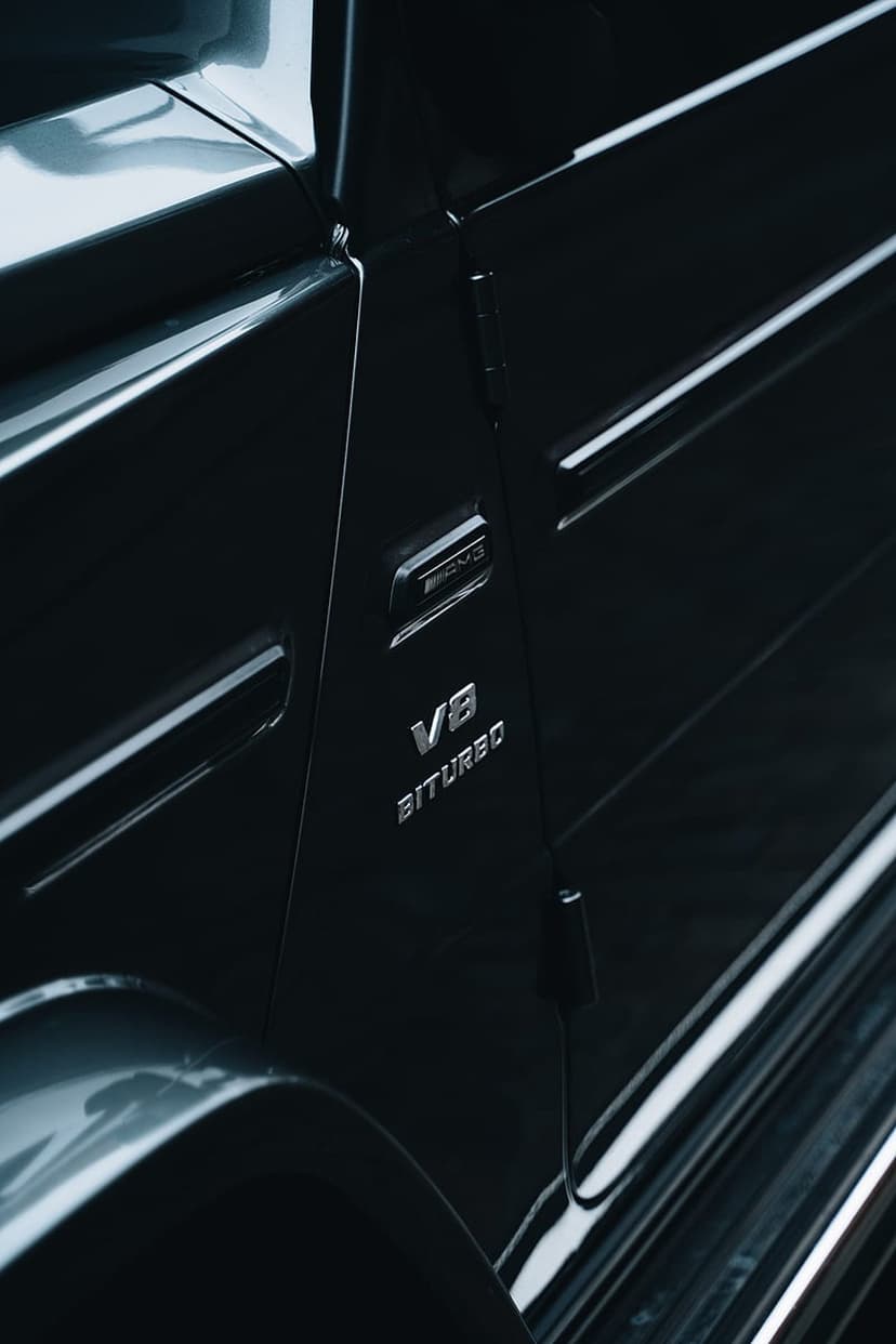 Mercedes-AMG V8 Biturbo chrome emblem mounted on a glossy black vehicle panel with sharp metallic reflections.