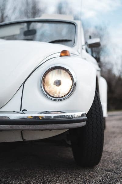 Close-up of a vintage white Volkswagen Beetle headlight