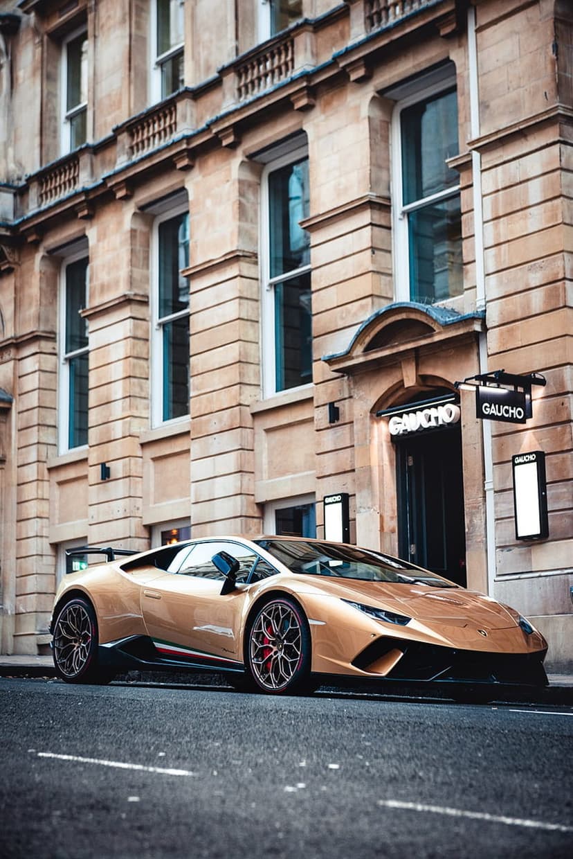 Gold Lamborghini supercar parked on a city street in front of a stone building with Gaucho restaurant signage