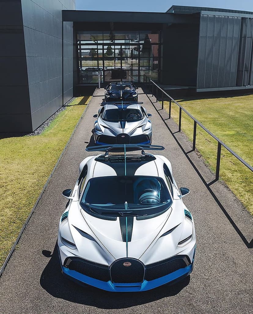 Three Bugatti Divo hypercars parked in a line inside a minimalist concrete building with soft overhead lighting.