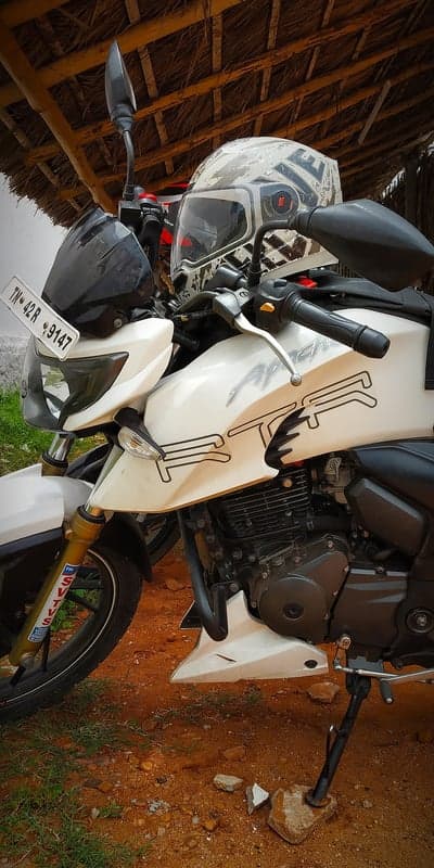 White Apache RTR motorcycle with helmet and license plate