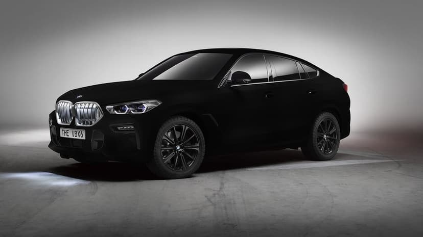 Vantablack BMW VBX6 luxury SUV with illuminated grille and headlights parked in a gray minimalist studio.