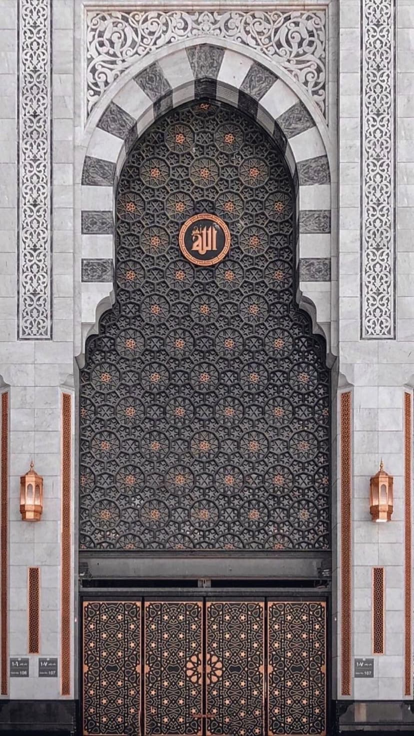 Circular Arabic calligraphy emblem centered on a marble archway with geometric patterns and hanging lanterns.