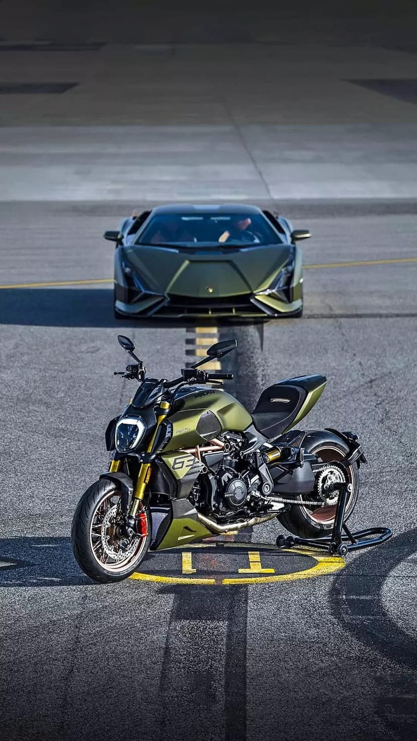 Lamborghini supercar and Ducati motorcycle in matte green parked on a dark tarmac road under soft light.