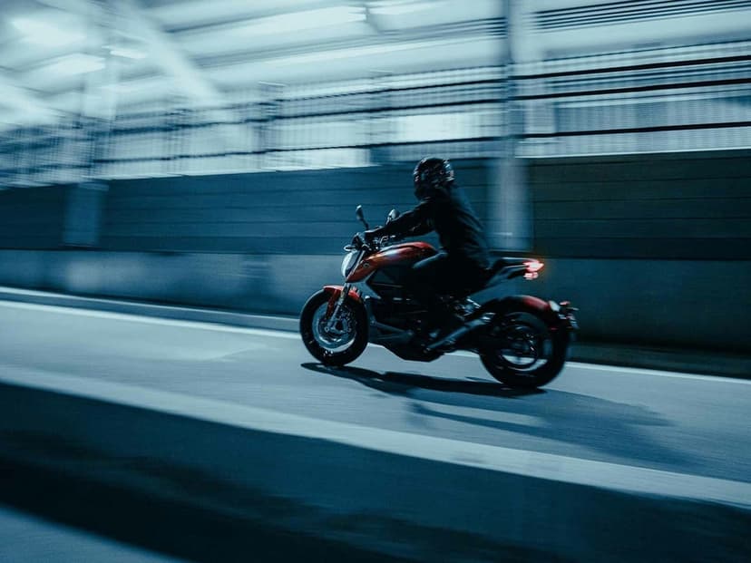 Red motorcycle rider speeding through a blurred urban tunnel with cool blue lighting and motion streaks.