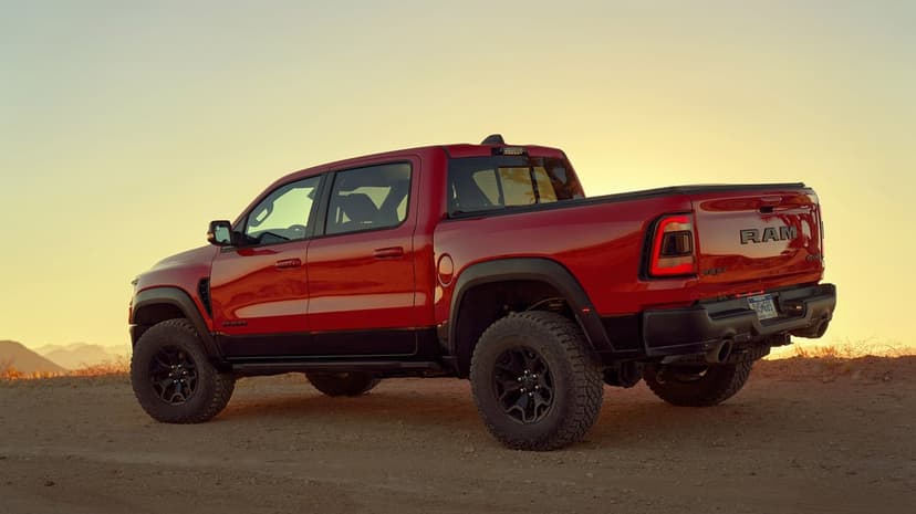 Red Ram TRX pickup truck on a desert trail at sunset with warm golden light and soft mountain silhouettes.
