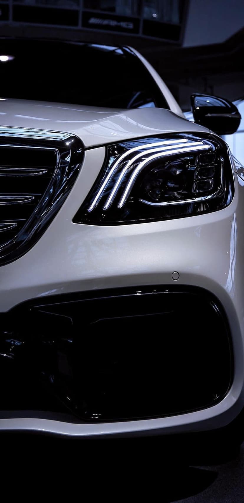 White Mercedes-Benz headlight and chrome grille featuring detailed LED daytime running lights and metallic accents.