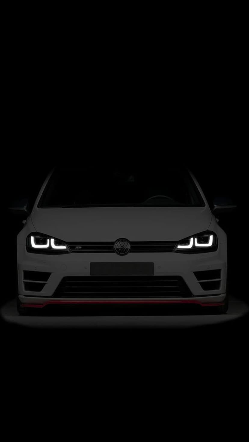 White Volkswagen Golf R front grille with glowing LED headlights and red accents against a black background.