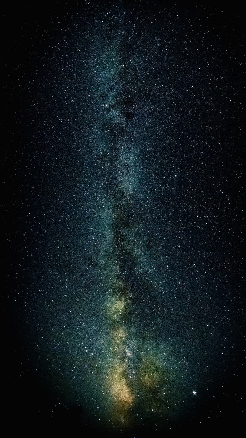 Milky Way galaxy's luminous band of stars and colorful nebulae stretching across a dark vertical night sky view.