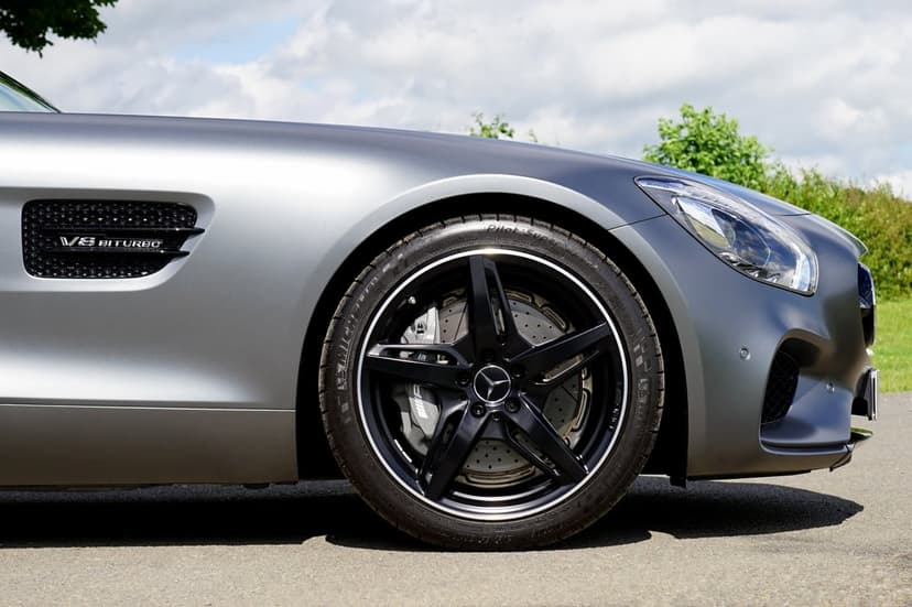 Mercedes-AMG GT R wheel and silver fender with a V8 Biturbo badge against a blurred greenery and sky background.