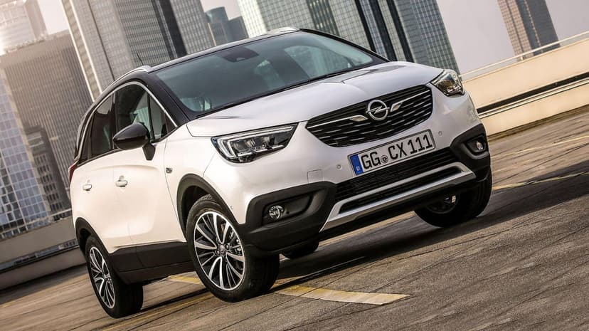 White Opel Crossland X SUV on a rooftop parking lot with skyscrapers and city buildings in the background.