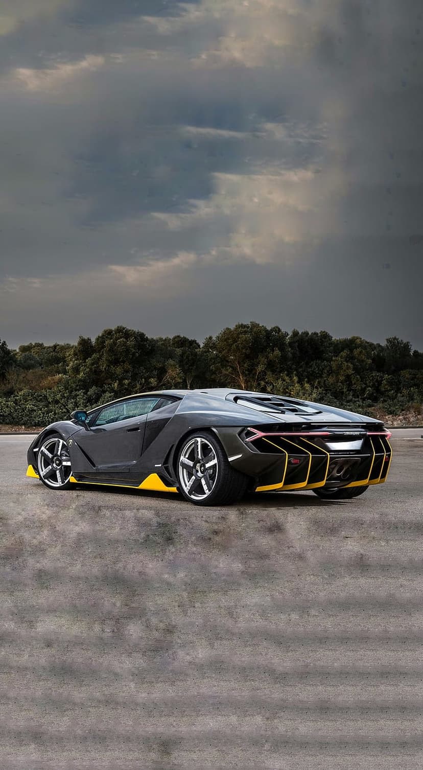 Lamborghini Centenario with yellow trim accelerates on asphalt under a dark and moody cloudy sky at dusk.